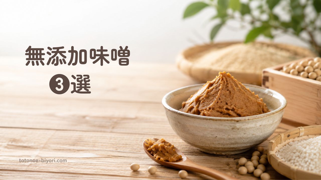 陶器の器に盛られた無添加味噌と、木のさじ・大豆・米麹